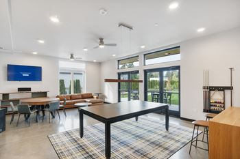 A modern living room with a black table and a flat screen tv mounted on the wall